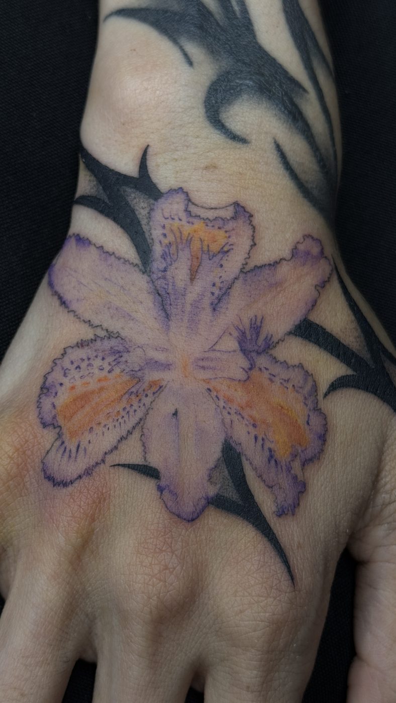 Tatuaje a color de flor en la mano